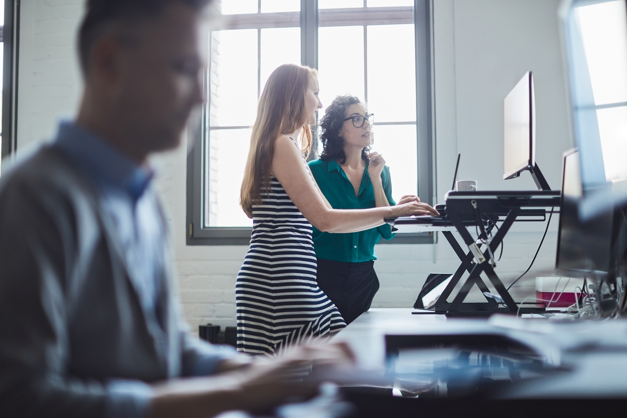 woman at standing desk and man sitting proper ergonomics